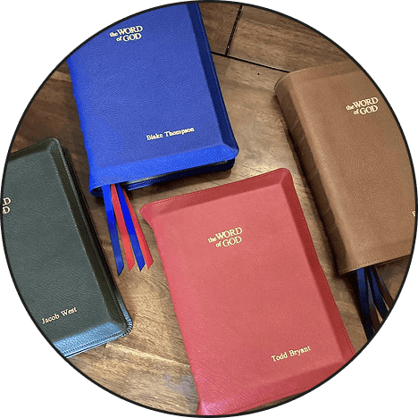 Christian prayer books with "the WORD of GOD" embossed on covers, on wooden surface.